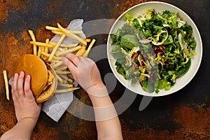 Child making choice between healthy salad and fast food