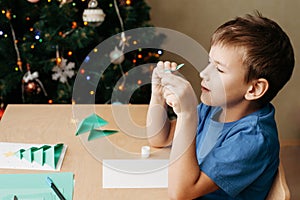 Child making Christmas card from paper. Step 5