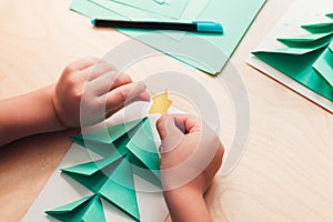 Child making Christmas card from paper. Step 6