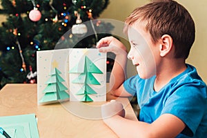 Child making Christmas card from paper. Step 8