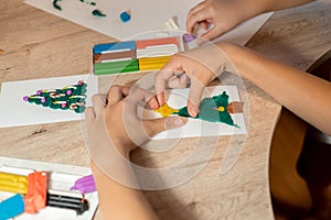 Child making Christmas decor from playdough at table