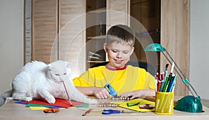 Child making Christmas decorations with cat on the table. Make christmas decoration with your own hands.