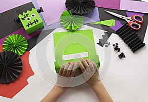 A child making decorum of Halloween from colored paper.