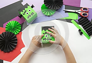 A child making decorum of Halloween from colored paper.