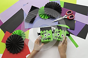 A child making decorum of Halloween from colored paper.