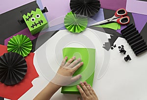 A child making a Frankenstein decorum of Halloween from colored paper.