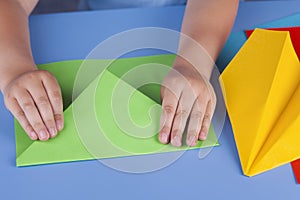 Child making a green paper plane