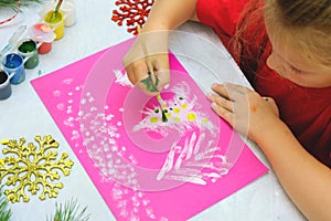 Child making a greeting card. Craft for children. Nice greeting card with a Christmas snowy forest. . Top view