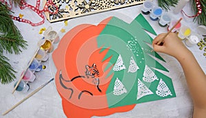 Child making a greeting card  Craft for children. Nice greeting card with a Christmas snowy forest. . Top view