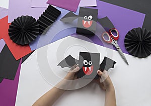 A child making Halloween decorations from colored paper.