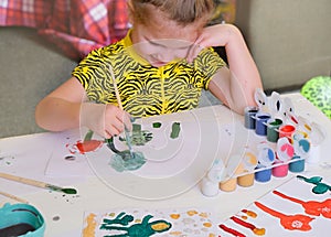 Child making homemade greeting card. A little girl paints  flowers as a gift for Mothers Day . Traditional play concept. Arts and