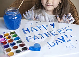 Child making homemade greeting card. A little girl paints a heart on a homemade greeting card as a gift for Father Day