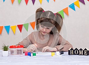 Child making homemade greeting card. Little girl paints heart on homemade greeting card as gift for Mother Day.