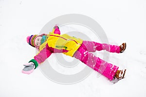 Child making snow angel. Kids play in winter park.