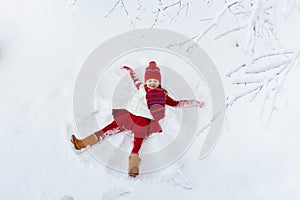 Child making snow angel. Kids winter outdoor fun