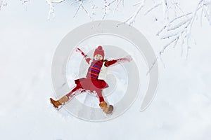 Child making snow angel. Kids winter outdoor fun.