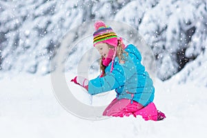 Child making snowman. Kids play in snow in winter