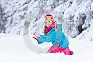 Child making snowman. Kids play in snow in winter