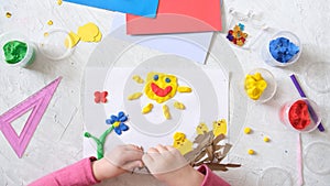 Child making spring card from colorful paper and plasticine, clay. Handmade. Concept of children`s creativity, handicrafts, craft