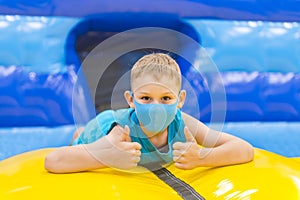 Child  with mask on colorful playground trampoline. Kids jump in inflatable bounce castle on kindergarten birthday party. Activity