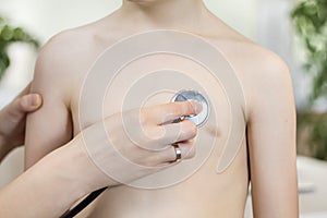 Child during medical examination in the office of a pediatrician. Medical examination with a chest stethoscope in a doctor`s offic