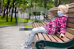 Child in a medical mask in profile in the park for a walk. andemic