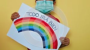 Child with medical mask and rainbow message in Castellano Spanish