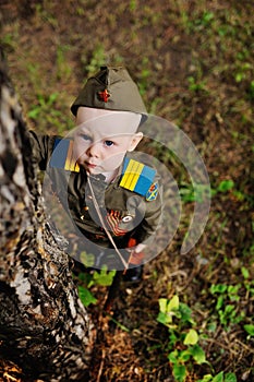 Child in military uniform against nature background