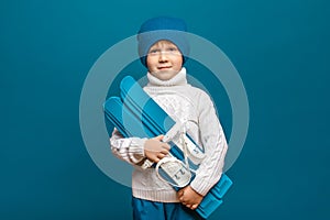 Child with mini skis in hands. Winter sports and leisure concept, studio shot.