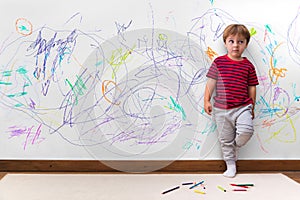 Child mischief. Boy with a distracted face because he drew the entire wall.