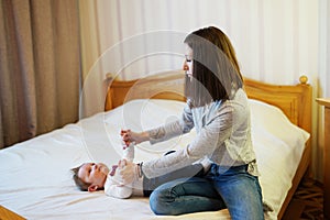 Child and mother on bed. Mom and baby boy playing in sunny bedroom. Parent and little kid relaxing at home. Family having fun