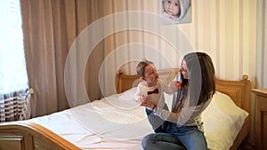 Child and mother on bed. Mom and baby boy playing in sunny bedroom. Parent and little kid relaxing at home. Family having fun