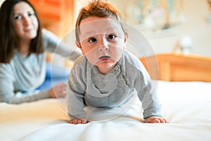 Child and mother on bed. Mom and baby boy playing in sunny bedroom. Parent and little kid relaxing at home. Family having fun