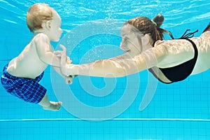 Child with mother dive in swimming pool