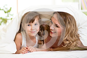Child and mother lying under blanket in bed