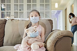 Child and mother in medical masks while coronavirus quarantined at home photo