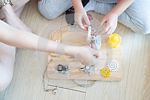 Child and mother are playing with busy board toy on the wooden floor together. Childrenâ€™s educational busy board toy for