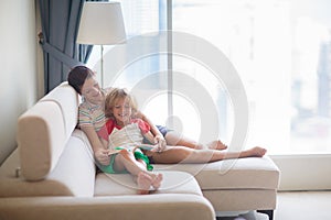 Child and mother read a book in sunny room