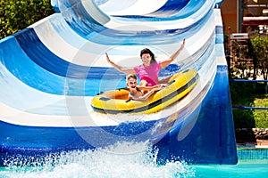 Child with mother on water slide at aquapark