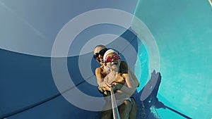 Child with mother on water slide at aquapark. Summer holiday.