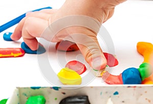 Child moulds from plasticine on table, hands with plasticine