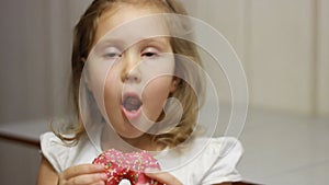 Child mouth bites rose donut. Closeup baby girl eating doughnut with glase. Delicious, sweet, sweettooth