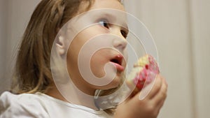 Child mouth bites rose donut. Closeup baby girl eating doughnut with glase. Delicious, sweet, sweettooth