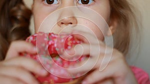 Child mouth bites rose donut. Closeup baby girl eating doughnut with glase. Delicious, sweet, sweettooth.