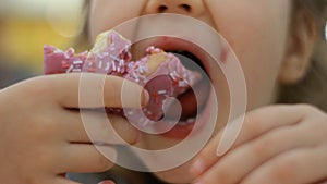 Child mouth bites rose donut. Closeup baby girl eating doughnut with glase. Delicious, sweet, sweettooth