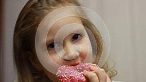 Child mouth bites rose donut. Closeup baby girl eating doughnut with glase. Delicious, sweet, sweettooth.