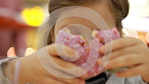 Child mouth bites rose donut. Closeup baby girl eating doughnut with glase. Delicious, sweet, sweettooth
