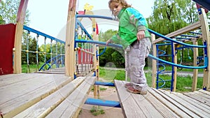 The child moves neatly over the bridge on the playground. Slow motion.
