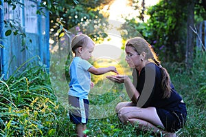 Child Nature discovery. The child throws grains of mother in hand. Photos of the child and mother, backlit