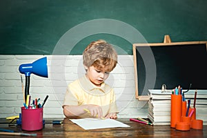 Child near chalkboard in school classroom. Funny little kids pointing up on blackboard. Little ready to study. Cute